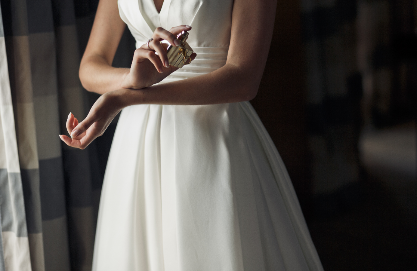woman in white dress spraying perfume, mid section crop