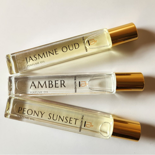 Three perfume bottles labeled 'Jasmine Oud', 'Amber', and 'Peony Sunset' on a light background.