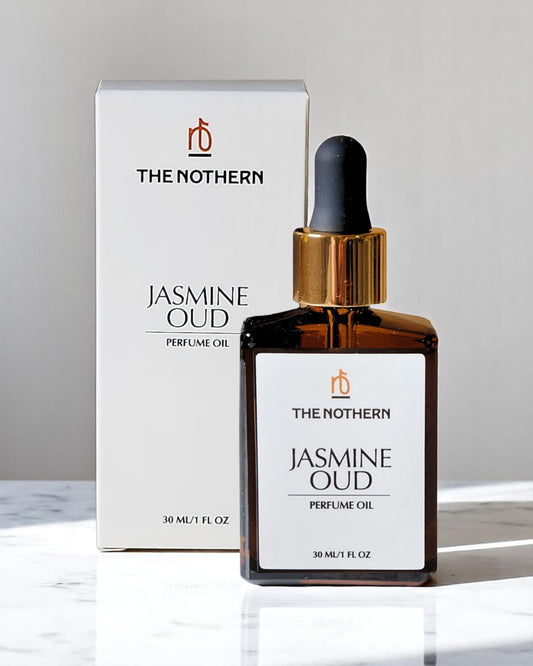 A bottle of Jasmine Oud Perfume Oil with a dropper cap, next to its packaging box. The box and bottle have white backgrounds with text and branding. | The Nothern