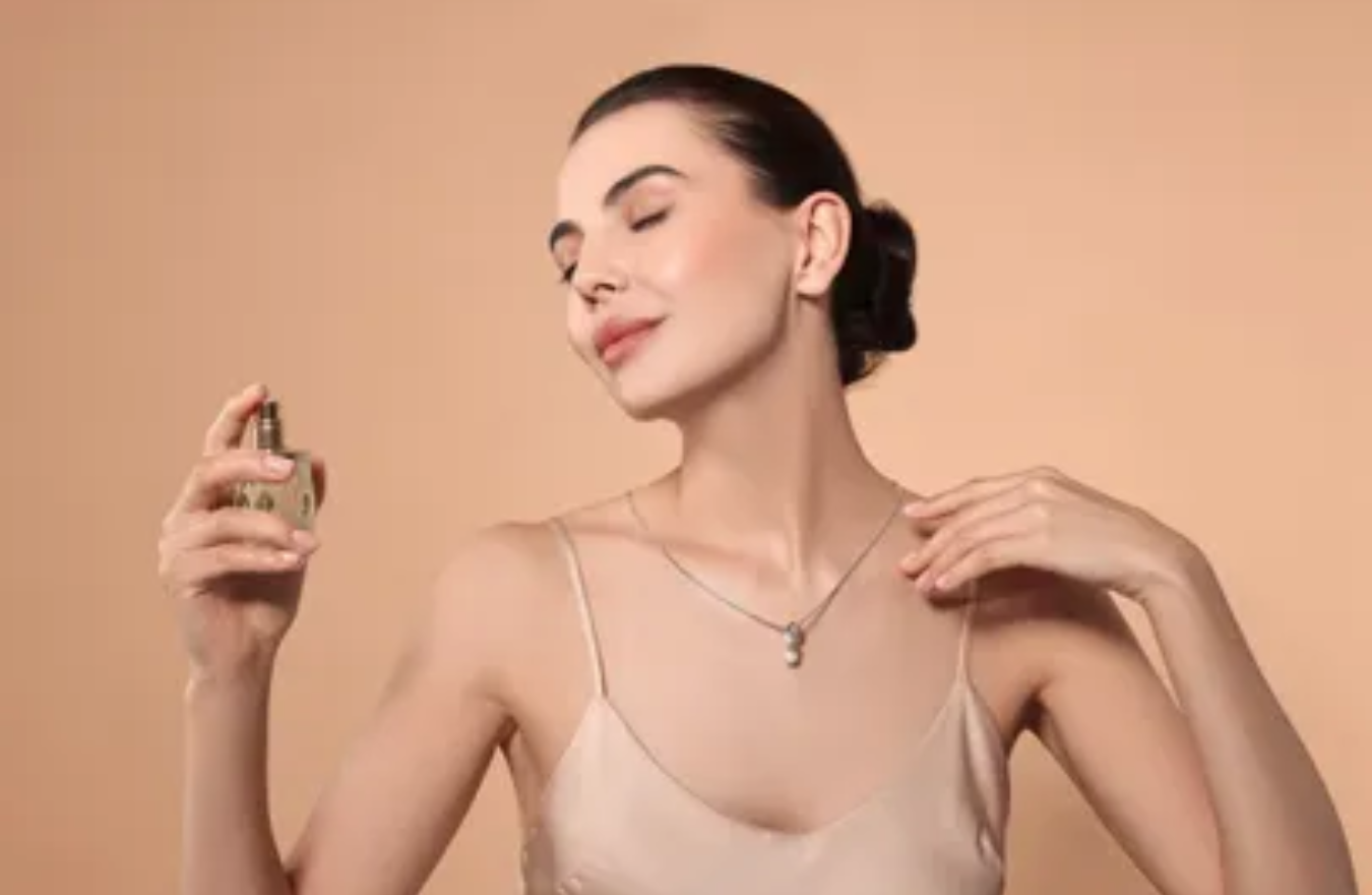 stock image of woman holding perfume bottle with eyes closed