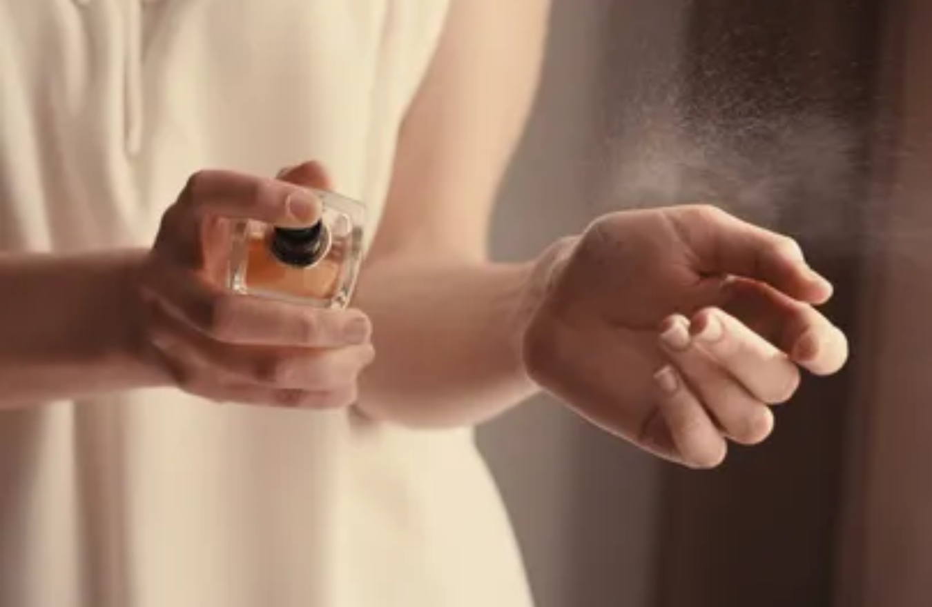 Stock image of woman spraying perfume on wrist