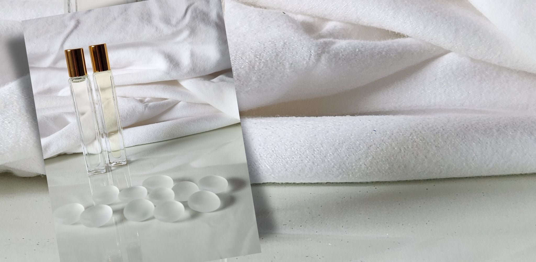 Two perfume bottles on a white surface with a white towel in the background